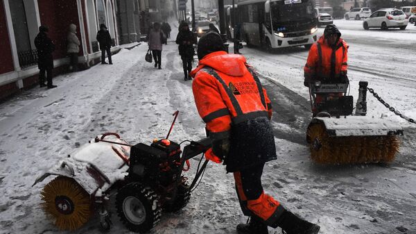 Сотрудники коммунальных служб убирают снег на улицах Владивостока после сильного снегопада