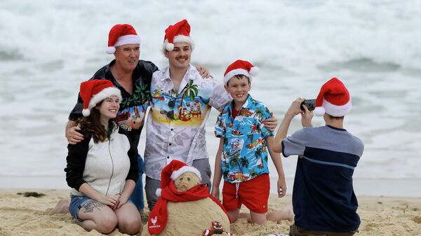 Семья фотографируется в рождественских колпаках на пляже в Сиднее, Австралия 
