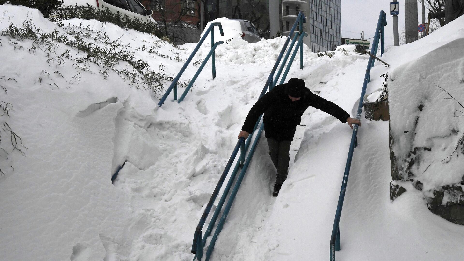 Мужчина идет по заснеженной лестнице на проспекте Красного Знамени во Владивостоке после сильного снегопада - РИА Новости, 1920, 10.01.2022