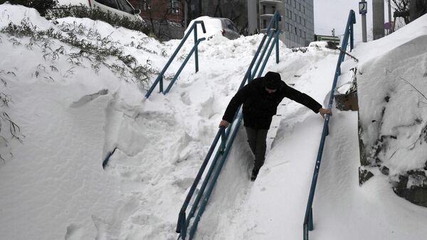 Мужчина идет по заснеженной лестнице после сильного снегопада. Архивное фото