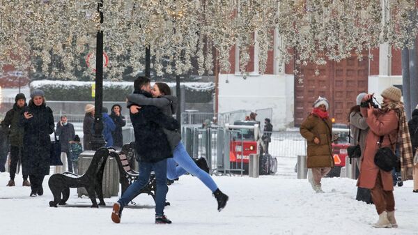 Прохожие фотографируются на Никольской улице в Москве после снегопада
