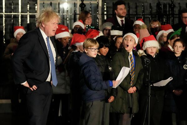 Премьер-министр Великобритании Борис Джонсон и детский хор во время церемонии зажжения огней рождественской елки на Даунинг-стрит в Лондоне
