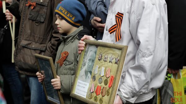 Люди несут портреты ветеранов Великой Отечественной войны в День Победы в Минске, Беларусь
