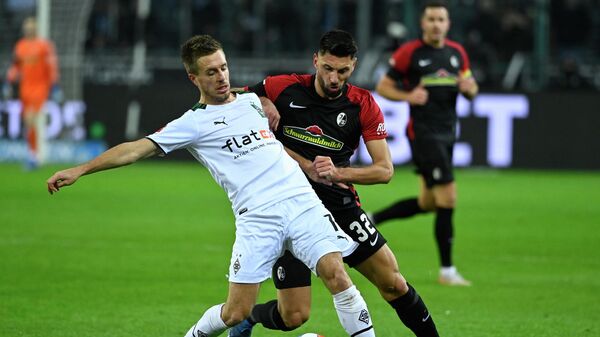 Moenchengladbach's German forward Patrick Herrmann (L) and Freiburg's Italian midfielder Vincenzo Grifo vie for the ball during the German first division Bundesliga football match Borussia Moenchengladbach v SC Freiburg in Moenchengladbach, western Germany, on December 5, 2021. (Photo by Ina Fassbender / AFP) / DFL REGULATIONS PROHIBIT ANY USE OF PHOTOGRAPHS AS IMAGE SEQUENCES AND/OR QUASI-VIDEO