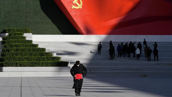 Мужчина возле скульптуры флага Коммунистической партии Китая возле Музея Коммунистической партии, в Пекине, Китай