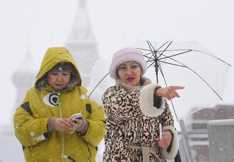 Люди на Красной площади в Москве во время снегопада