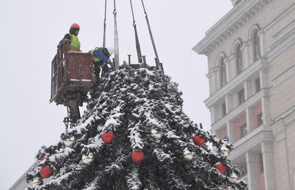 Рабочие устанавливают новогоднюю елку на Манежной площади в Москве во время снегопада