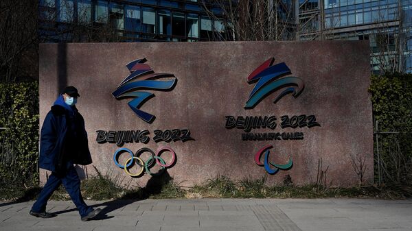 A man walks past the logos of the Beijing 2022 Winter Olympics and Paralympic Winter Games in Shougang Park, one of the sites for the Beijing 2022 Winter Olympics, in Beijing on December 7, 2021. (Photo by Noel Celis / AFP)
