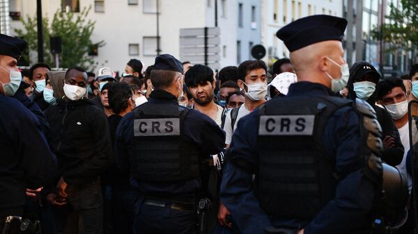 Французская полиция перед беженцами во время эвакуации импровизированного лагеря в пригороде Парижа