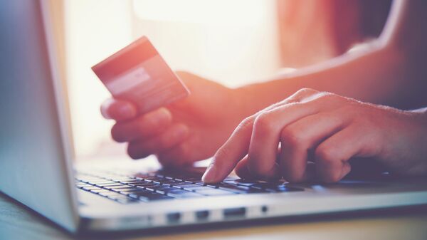 Девушка держит в руках банковскую карту для оплаты онлайн-покупок