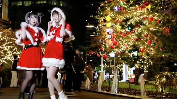 Девушки в костюмах Санта-Клауса фотографируются перед рождественскими украшениями в Токио