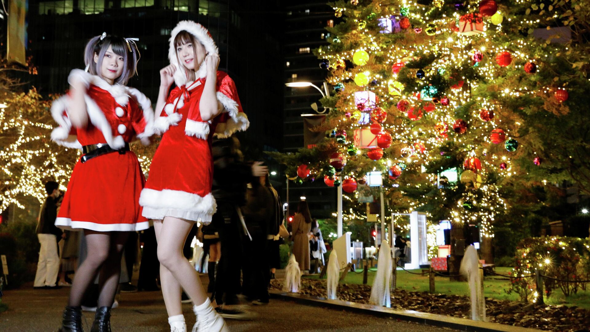 Девушки в костюмах Санта-Клауса фотографируются перед рождественскими украшениями в Токио - РИА Новости, 1920, 13.12.2021
