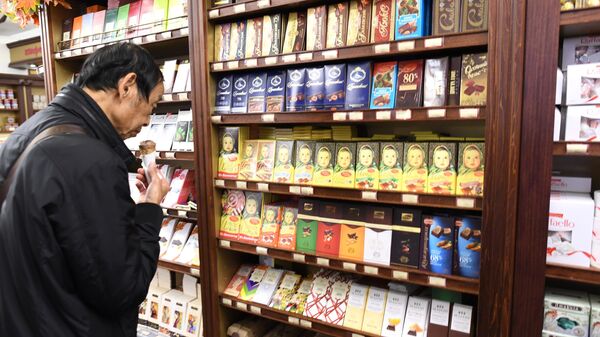 Мужчина выбирает шоколад в кондитерском отделе в магазине 