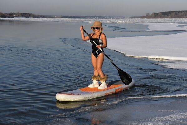 Активистка, пропагандирующая здоровый и активный образ жизни, катается на сапсерфинге по реке Обь в Новосибирске во время акции Белые пляжи Сибири, приуроченной к первому дню зимы