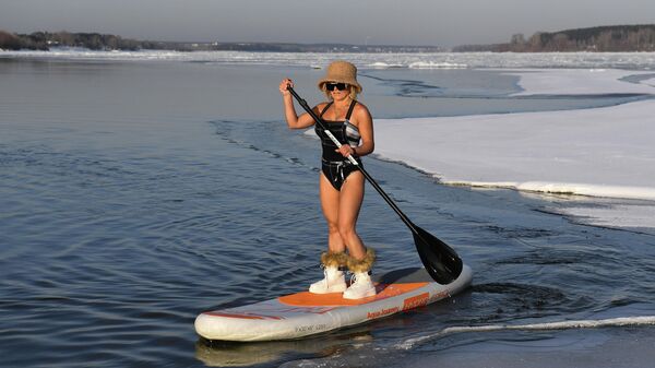 Активистка, пропагандирующая здоровый и активный образ жизни, катается на сапсерфинге по реке Обь в Новосибирске во время акции Белые пляжи Сибири, приуроченной к первому дню зимы