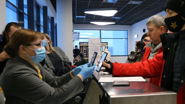 Сотрудница Международного аэропорта Хабаровск имени Г. И. Невельского проверяет у пассажира наличие QR-кода