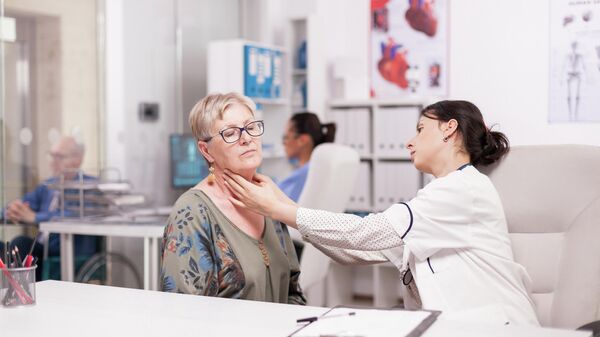 Врач осматривает щитовидную железу пациентки