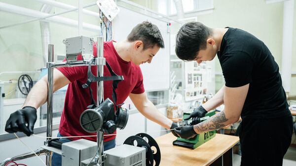 Молодые ученые ТПУ Игорь Акимченко и Александр Воробьёв получают филамент для 3D-принтера
