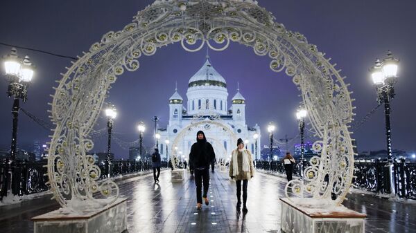 Молодые люди на Патриаршем мосту на фоне храма Христа Спасителя в Москве
