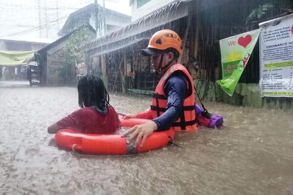 Сотрудник филиппинской береговой охраны проводит эвакуацию пострадавшего от наводнения жителя Кагаян-де-Оро