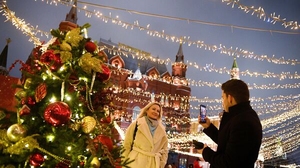 Люди фотографируются у новогодней елки на Манежной площади в Москве