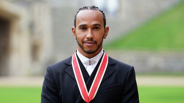 Mercedes' British F1 driver Lewis Hamilton poses with his medal after being appointed as a Knight Bachelor (Knighthood) for services to motorsports, by the Britain's Prince Charles, Prince of Wales, during a investiture ceremony at Windsor Castle in Windsor, west of London on December 15, 2021. - Lewis Hamilton received his knighthood on Wednesday as the British driver comes to terms with controversially losing the Formula One world title. (Photo by Andrew Matthews / POOL / AFP)