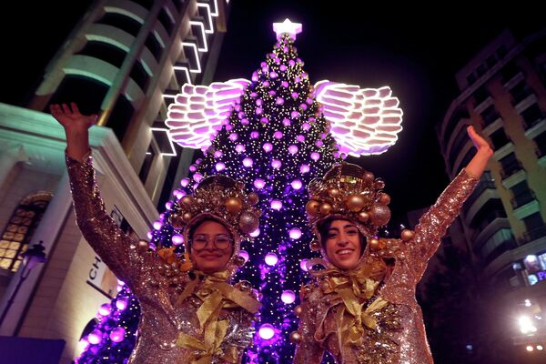 Девушки у рождественской елки во время празднования Рождества на площади Сассин в районе Ахрафие в Бейруте, Ливан