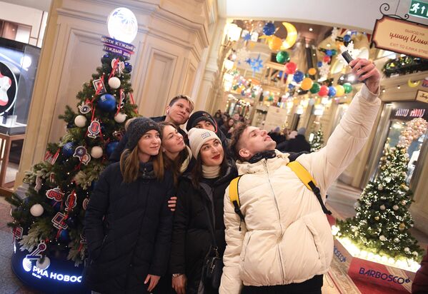 Молодые люди фотографируются у новогодней елки агентства Россия сегодня в ГУМе