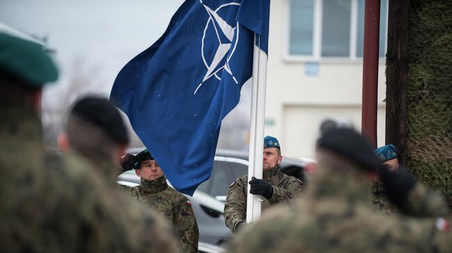 Польские военнослужащие поднимают флаг НАТО во время торжественной церемонии празднования 20-летия присоединения Чехии, Венгрии и Польши к блоку 