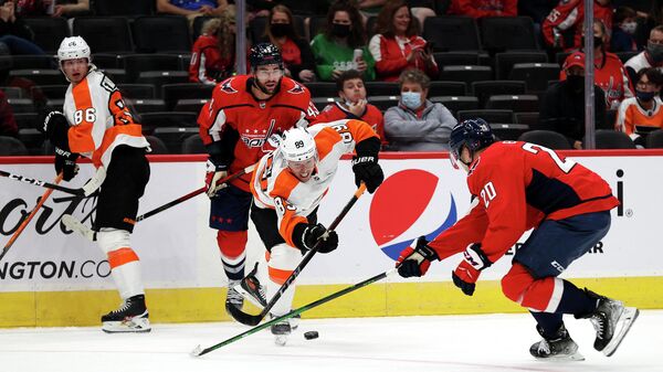 WASHINGTON, DC - OCTOBER 08: Cam Atkinson #89 of the Philadelphia Flyers passes the puck in front of Lars Eller #20 of the Washington Capitals in the second period during a preseason game at Capital One Arena on October 08, 2021 in Washington, DC.   Rob Carr/Getty Images/AFP (Photo by Rob Carr / GETTY IMAGES NORTH AMERICA / Getty Images via AFP)