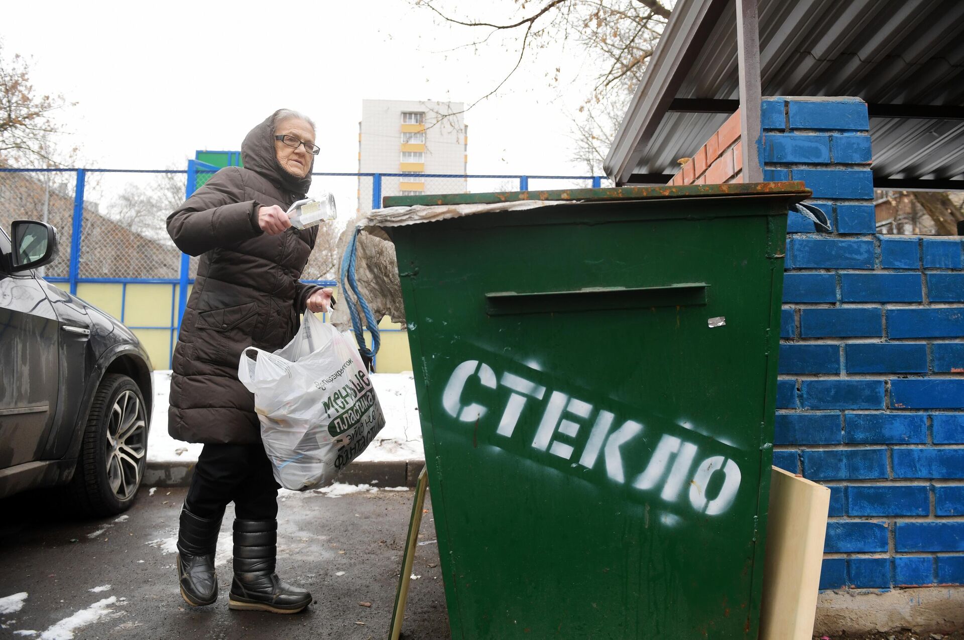 Женщина выкидывает стеклянную тару в контейнер для сбора отходов в одном из дворов в Москве - РИА Новости, 1920, 22.12.2021