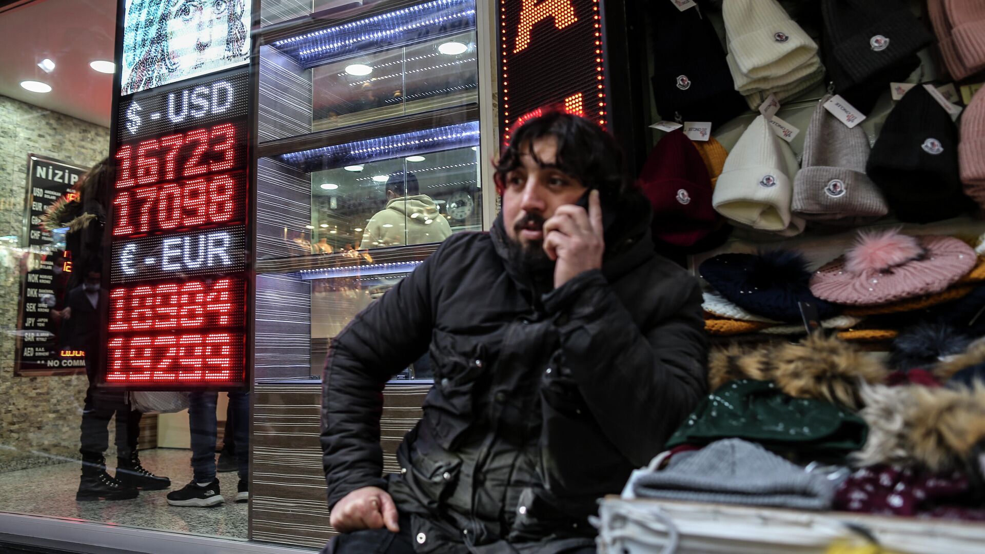 Мужчина разговаривает по телефону рядом с пунктом обмена валюты в коммерческом районе в районе Эминёню в Стамбуле, Турция - РИА Новости, 1920, 23.12.2021