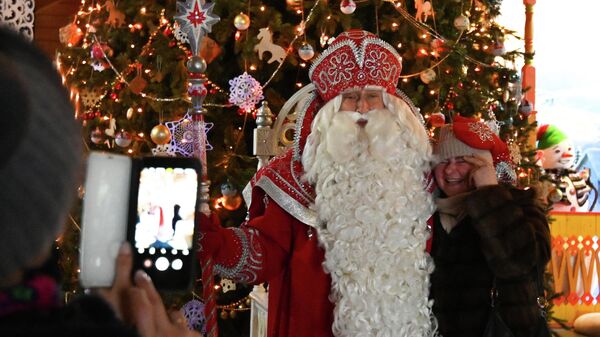 Посетительница делает совместное фото с Дедом Морозом в его Вотчине в Великом Устюге