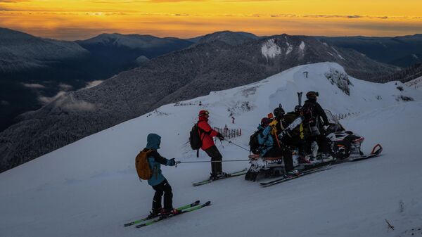 Отдыхающие едут на снегоходе на горнолыжном курорте Роза Хутор в Сочи
