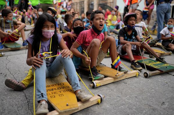 Дети участвуют в традиционной уличной гонке карруча на деревянных тележках в Каракасе