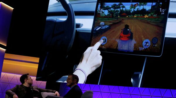 Илон Маск смотрит демонстрацию видеоигры в автомобиле Tesla Model 3