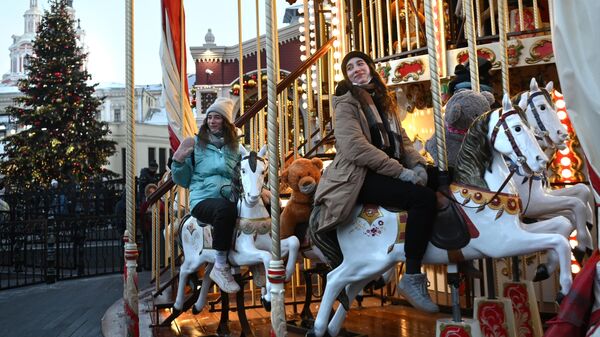 Гости катаются на праздничной карусели на площадке фестиваля Путешествие в Рождество на Площади Революции в Москве