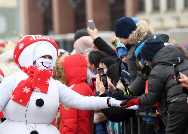 Аниматор в костюме снеговика общается с детьми во время встречи сказочного поезда Деда Мороза, прибывшего на железнодорожный вокзал в Казань