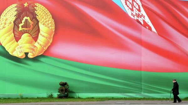 Мужчина проходит мимо граффити с флагом Белоруссии