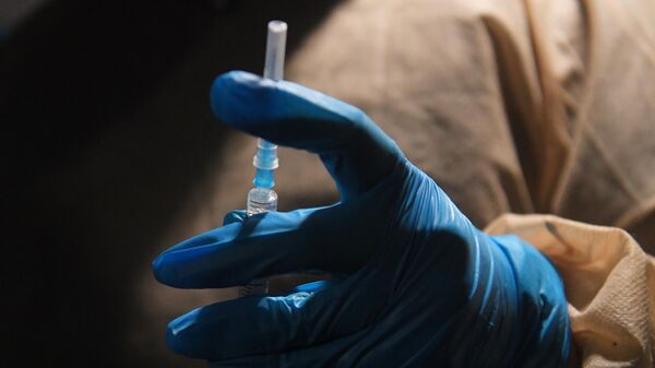 Медицинский работник держит в руке шприц с вакциной от COVID-19 