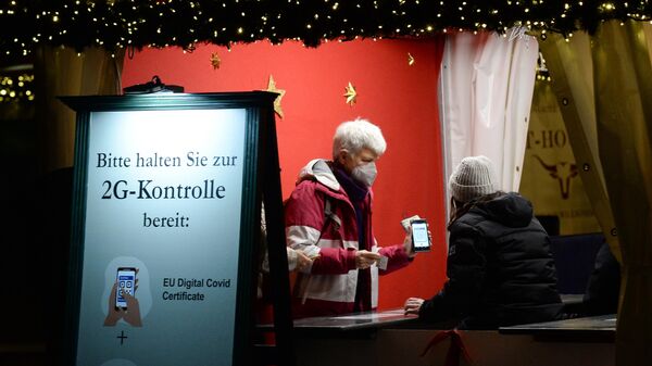 Проверка QR-кодов на входе традиционного рождественского базара на площади Жандарменмаркт в Берлине