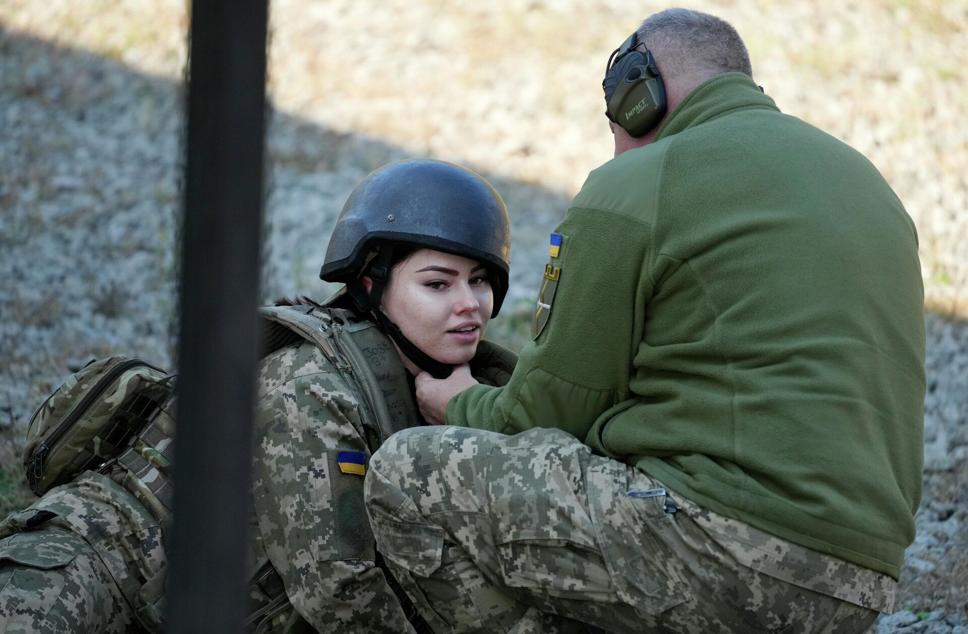 Военнослужащий поправляет шлем женщины-резервиста территориальных сил обороны Украины на военном полигоне под Киевом - РИА Новости, 1920, 20.06.2025