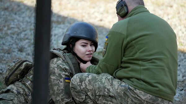 Военнослужащий поправляет шлем женщины-резервиста территориальных сил обороны Украины на военном полигоне под Киевом