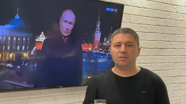 Украинский депутат Виталий Градинар поздравляет граждан с Новым годом на фоне экрана с портретом Президента России Владимира Путина