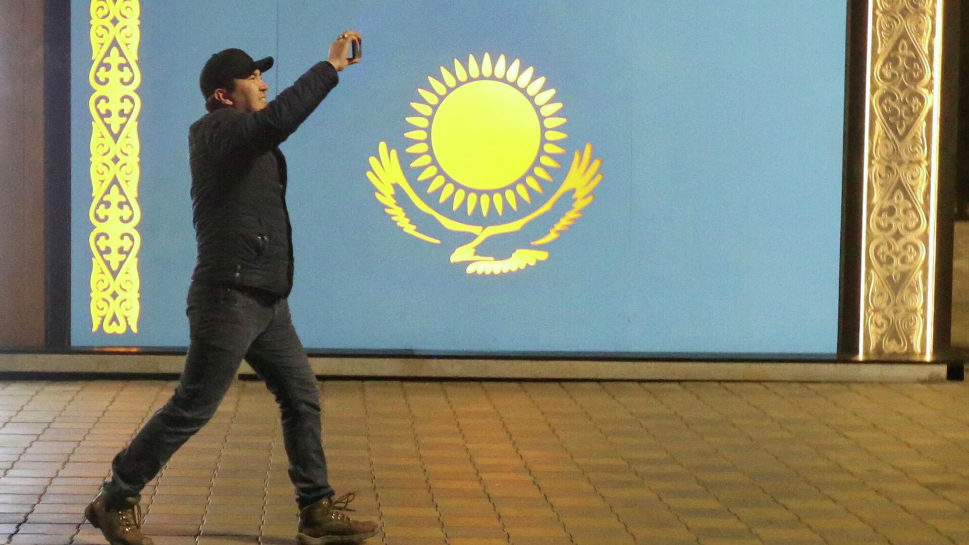 Мужчина проходит мимо флага Казахстана во время акции протеста против повышения цен на газ в Алма-Ате - РИА Новости, 1920, 05.01.2022