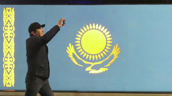 Мужчина проходит мимо флага Казахстана во время акции протеста против повышения цен на газ в Алма-Ате