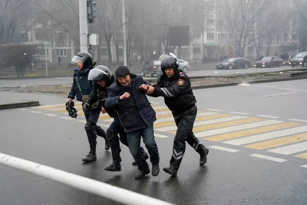 Сотрудники полиции задерживают участника акции протеста в Алма-Ате, Казахстан