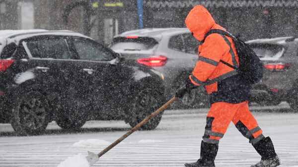 Сотрудник коммунальной службы убирает снег 