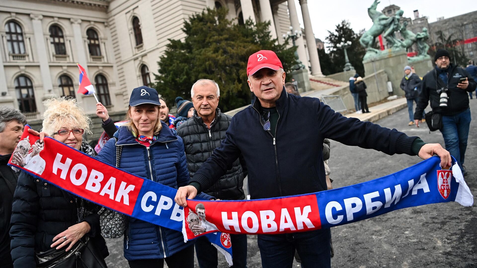 Srdan Djokovic (R) and  Dijana Djokovic (L), father and mother of Serbian tennis player Novak Djokovic, hold a scarf reading Novak Serbia as they attend a rally in front of Serbia's National Assembly in Belgrade, on January 6, 2022, held to protest against the Australia's government decision to revok their son's visa, on his arrival in Melbourne where he was to defend his Australian Open tennis title. - The tennis world number one player is set to spend the night in an immigration detention facility in Australia, after winning a temporary reprieve in his deportation from Australia. The vaccine-sceptic Serb was detained having failed to provide appropriate evidence of double vaccination, or a medical exemption needed to enter the country. (Photo by ANDREJ ISAKOVIC / AFP) - РИА Новости, 1920, 06.01.2022