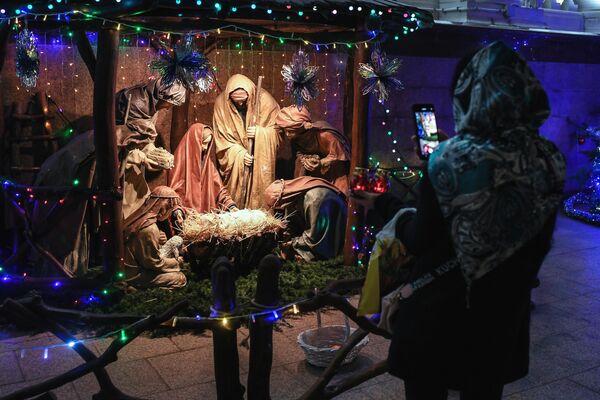 Женщина фотографирует Рождественский вертеп на территории Храма Трех Святителей в Симферополе
